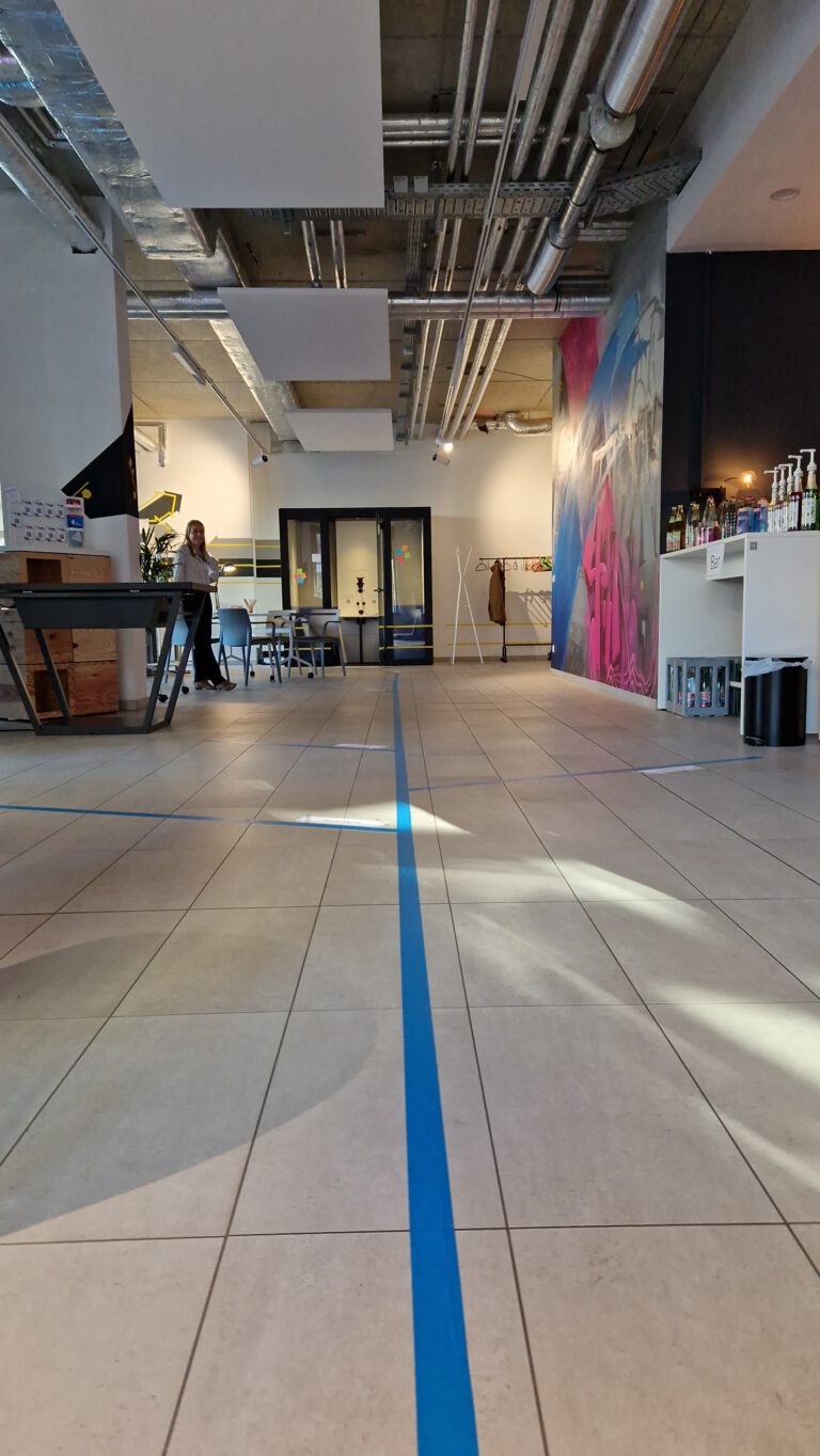 Innenraum des 4transferLabs. große Fliesenfläche mit blauem aufgeklebtem Band das als Fußbodenorientierung dient