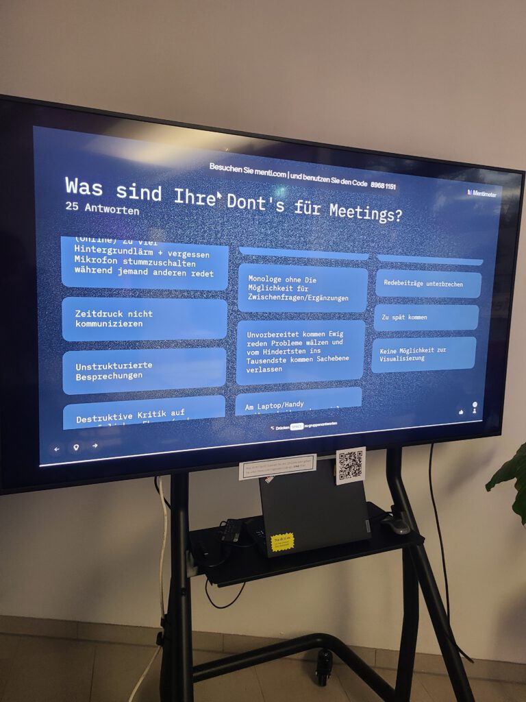 Monitor mit digitaler Anzeige. Überschrift: Was sind Ihre Dont's bei Meetings? Darunter Antworten, die Gäste eingegeben haben, unter anderem: Zeitdruck nicht kommunizieren