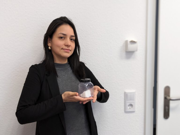 eine Frau präsentiert eine Probe in einem Kunststoffgefäß mit Schraubdeckel